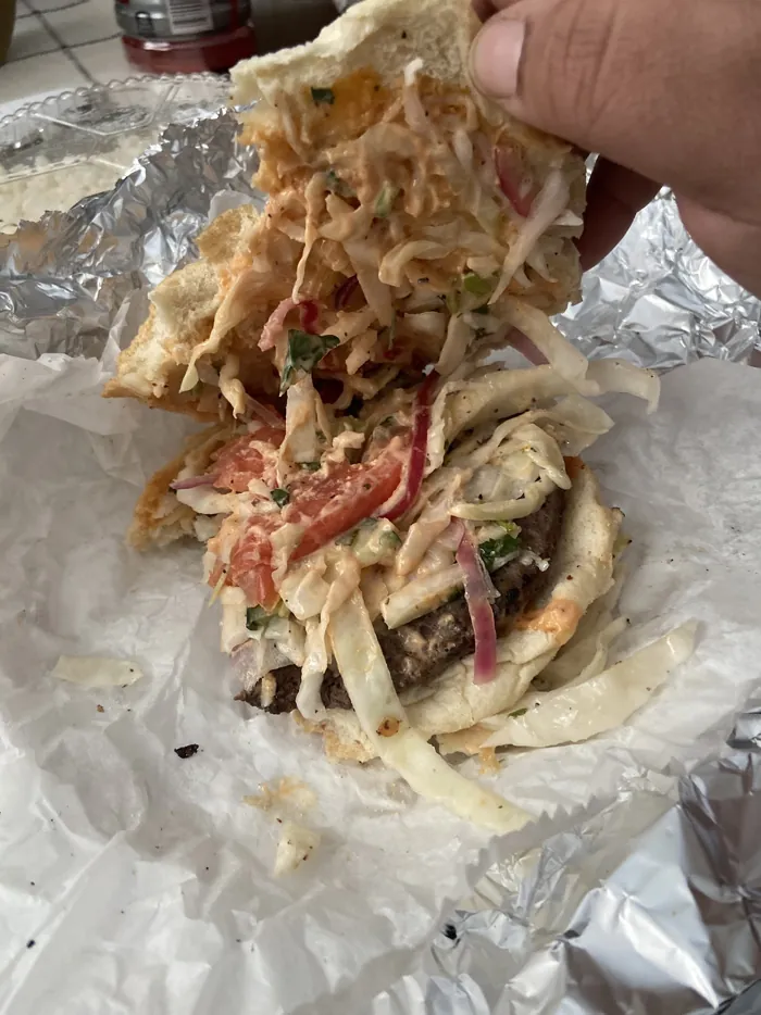 Fried chicken over green plantain chips with cabbage slaw and sauce, wrapped in foil