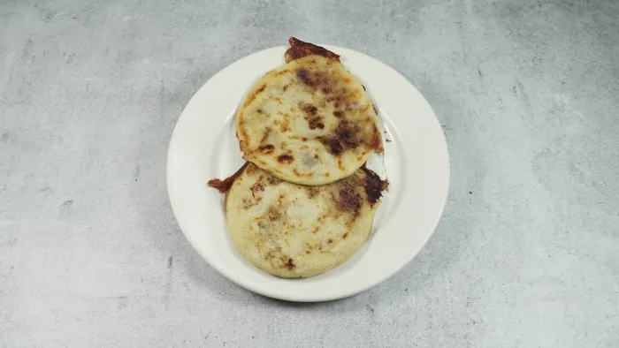 Two griddled pupusas on a white plate